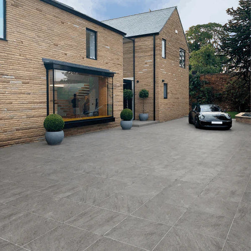 Modern home with grey stone-effect outdoor porcelain tiles used across a large driveway and patio area.