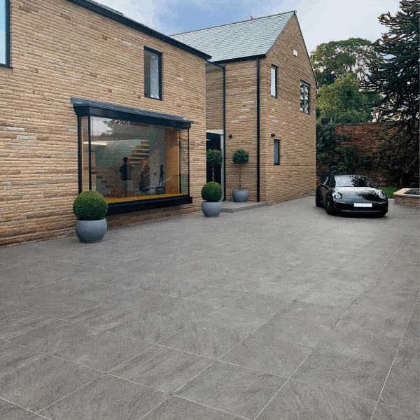 Modern home with grey stone-effect outdoor porcelain tiles used across a large driveway and patio area.