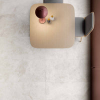 Beige square table with a few items on a light gray floor