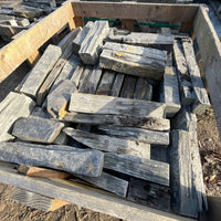 Stack of gray stone slabs on a wooden pallet outdoors