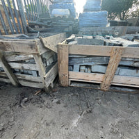 Stacks of wooden crates with concrete blocks inside on a concrete floor.