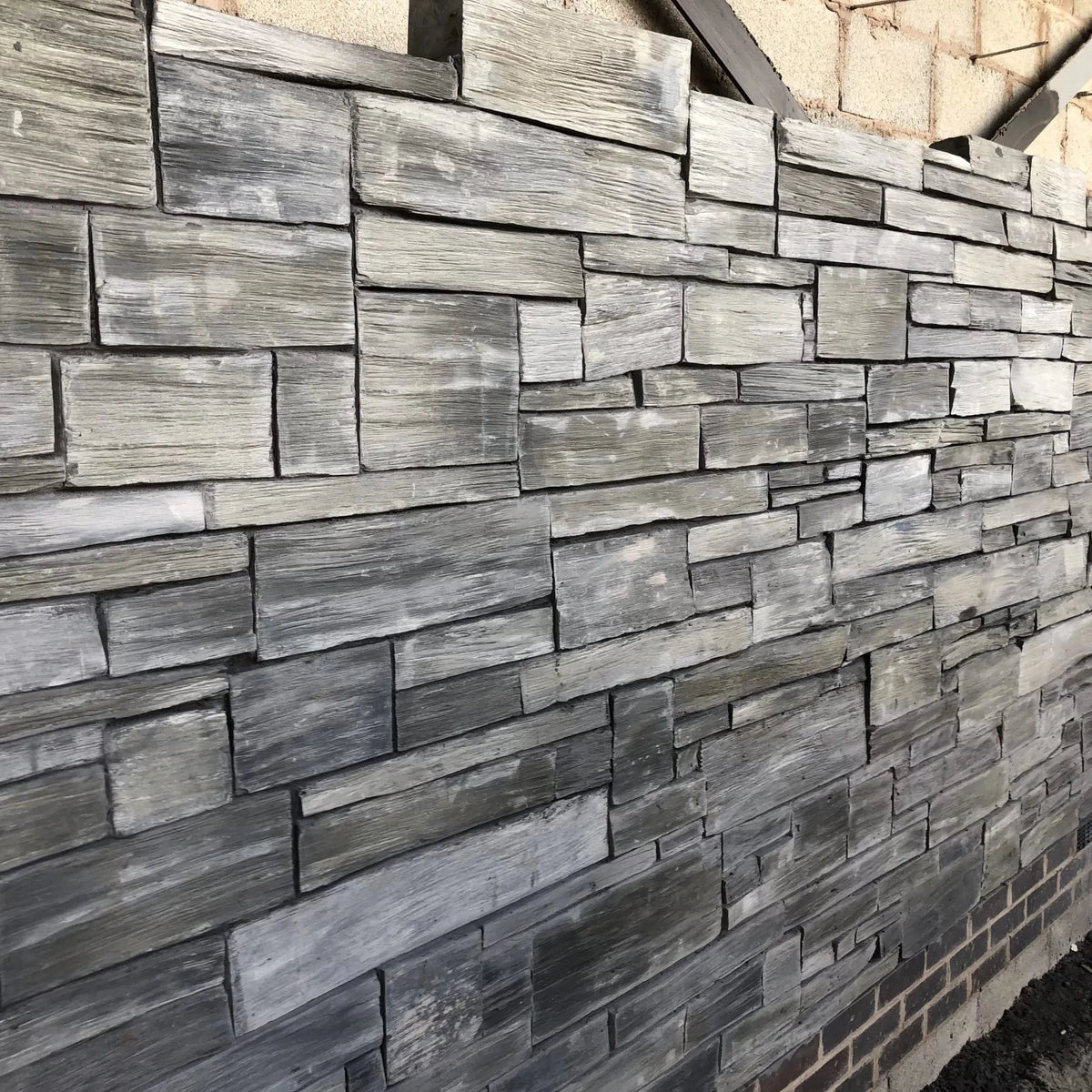 Wall made of stacked stone slabs in various shades of gray.