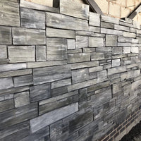 Wall made of stacked stone slabs in various shades of gray.