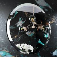 Round mirror with decorative lighting fixture on a black marble wall.