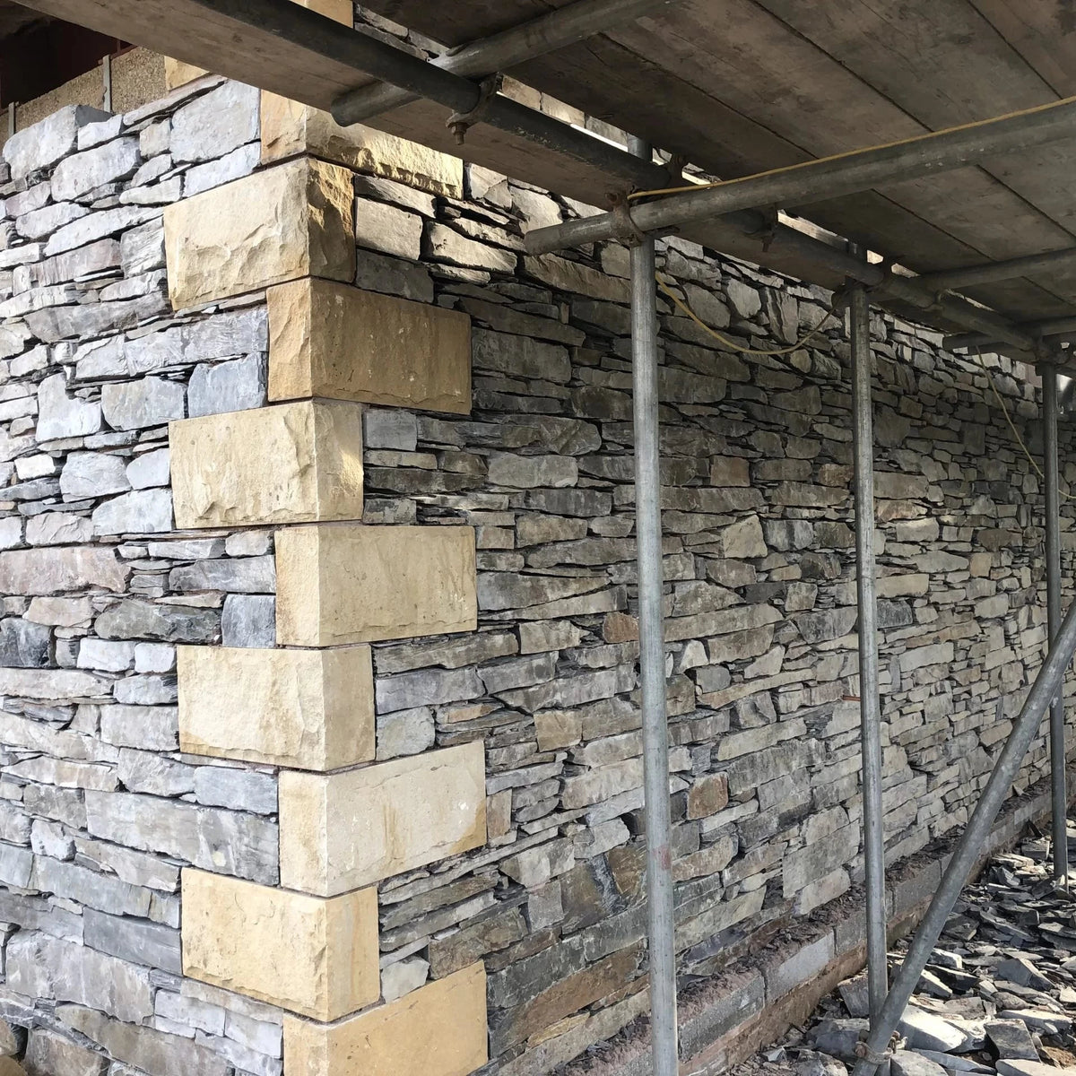 Stone wall under construction with scaffolding
