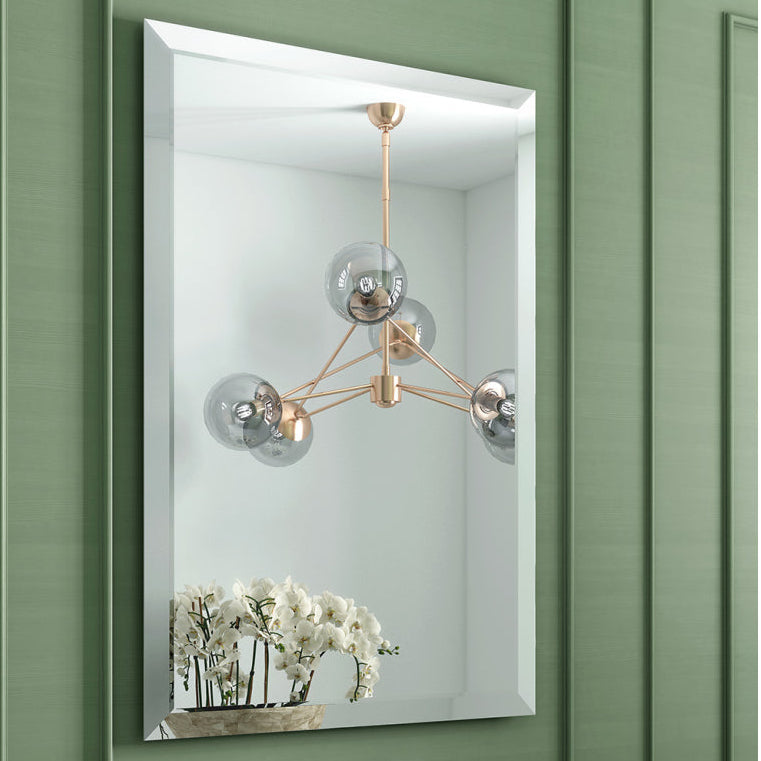 Bathroom with green paneling, black sink, and decorative mirror.