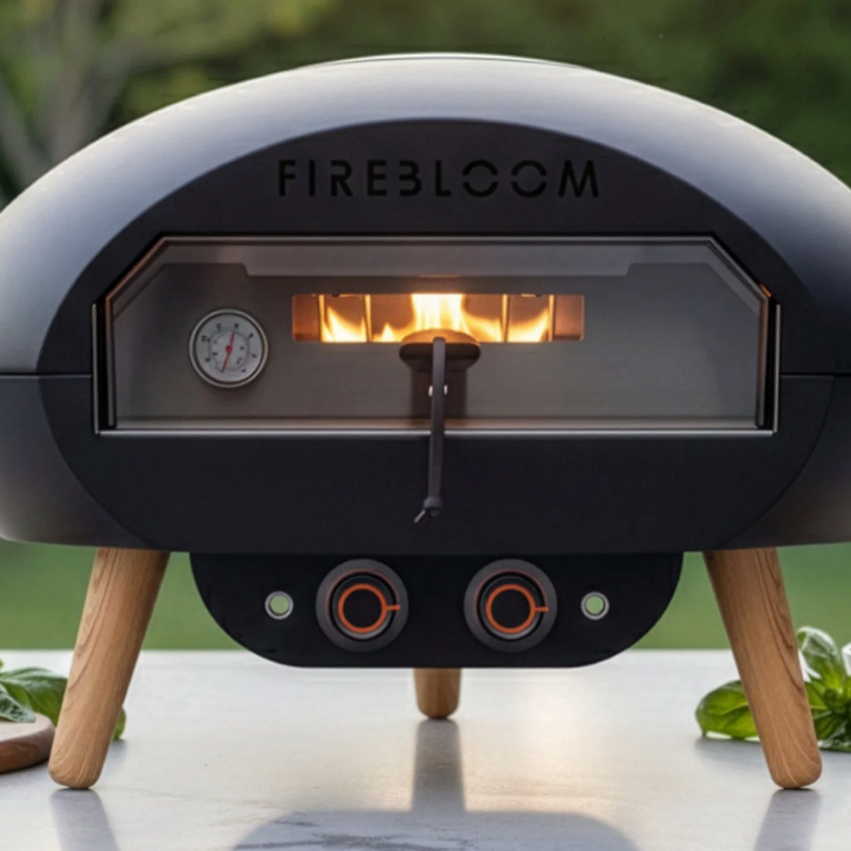 Black portable pizza oven with 'Fireloom' branding on a table with ingredients.