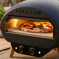 Firebloom outdoor pizza oven with a pizza inside, on a patio with ingredients in the background.