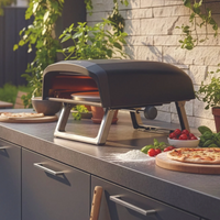 Outdoor kitchen scene with a portable pizza oven, people dining at a table, and various kitchen items.