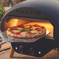 Firebloom pizza oven with a pizza inside, on a wooden surface.