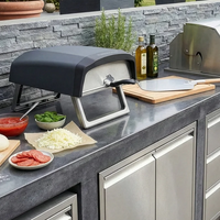 Outdoor kitchen setup with pizza oven, grill, and ingredients on a countertop.
